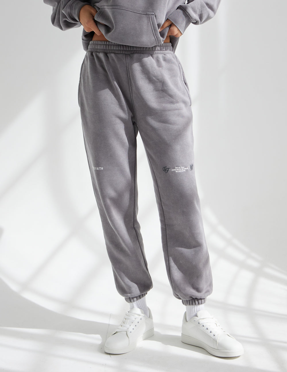 Dark gray unisex sweatpants with ribbed cuffs, side seams, small leg logo