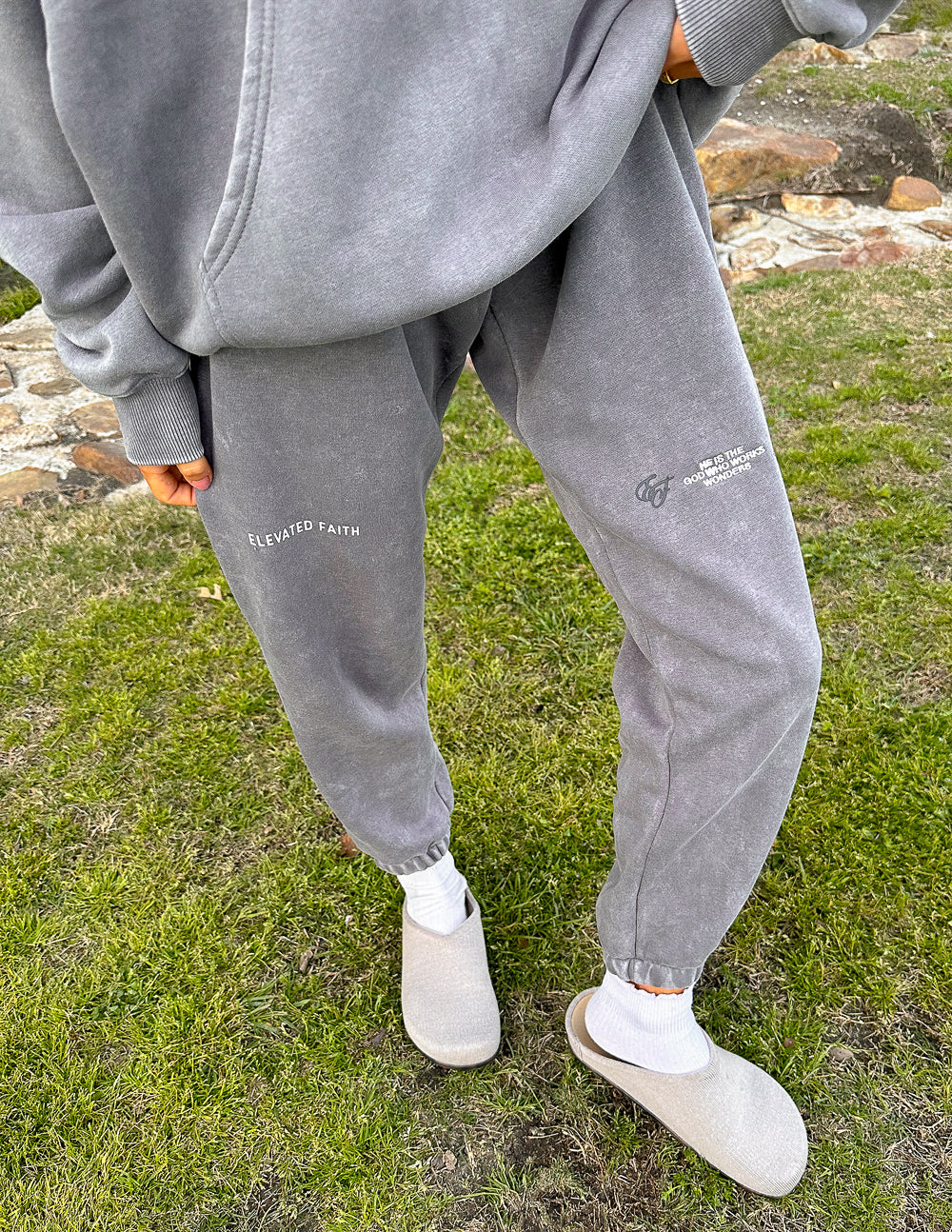 Dark gray unisex sweatpants with jogger cuffs and "CELEBRATED FAITH" leg text