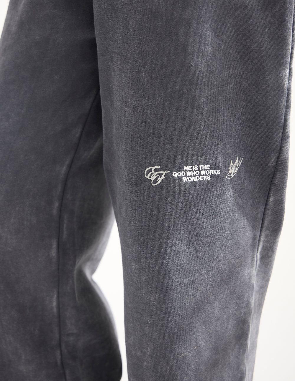 Charcoal wide-leg sweatpants detail with embroidered slogan and wing logo on leg