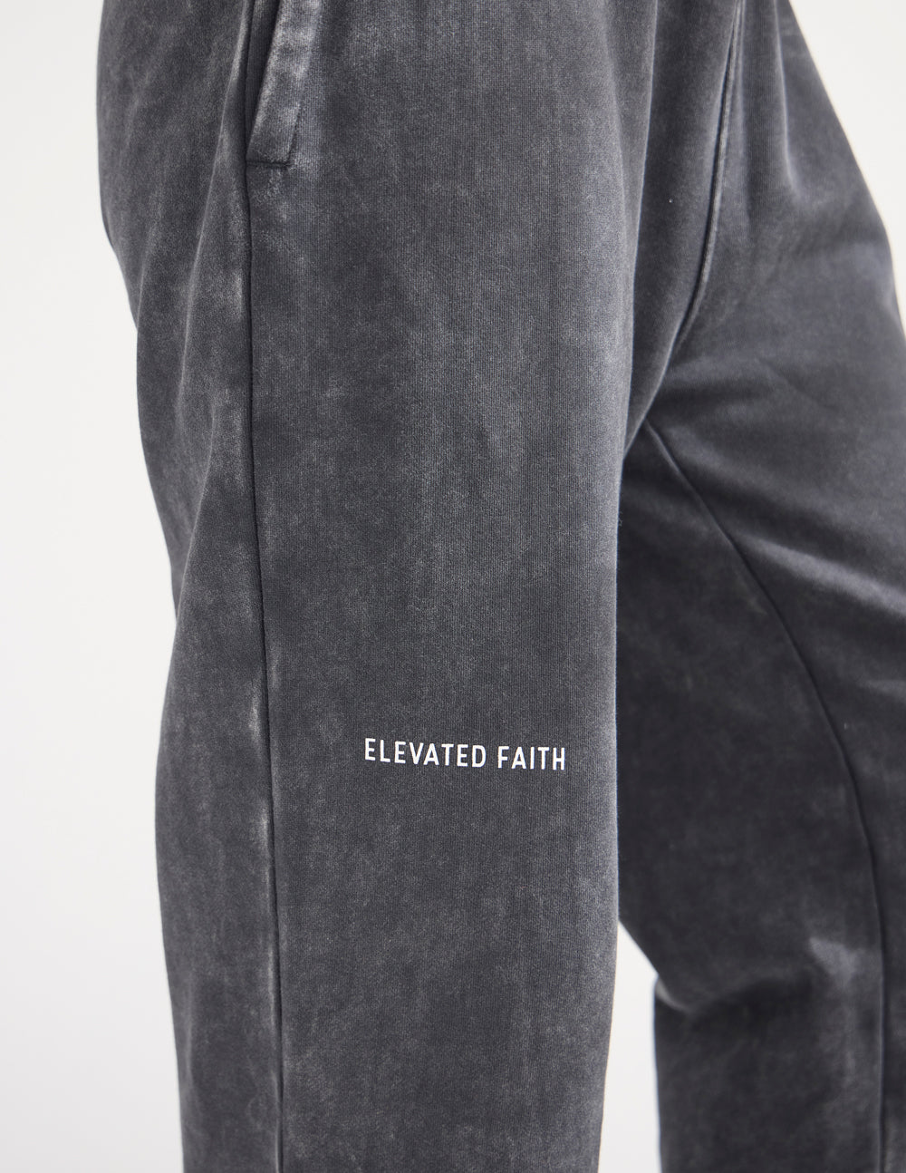 Charcoal wide-leg sweatpants close-up showing centered wordmark on leg