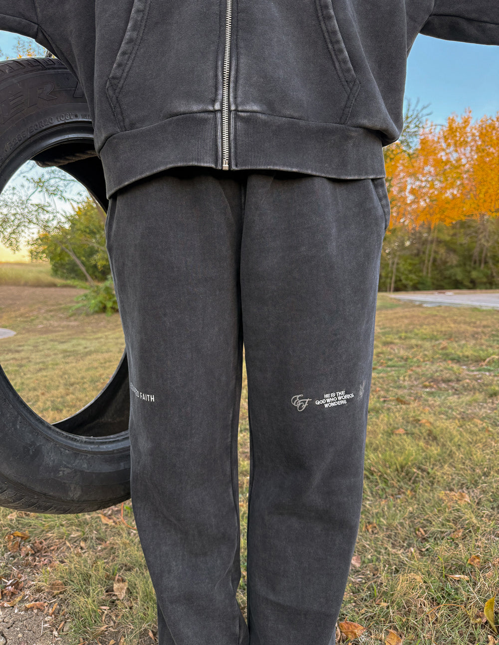 Dark charcoal wide-leg sweatpants with zip fly and small logo on thigh