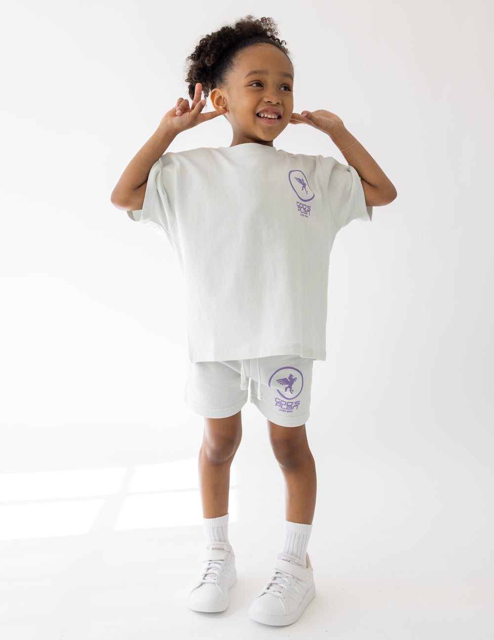 White kids racing shorts with purple logo print and elastic waistband
