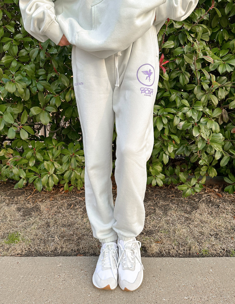 Light cream unisex sweatpants with purple logo print on thigh and cuffed ankle cuffs