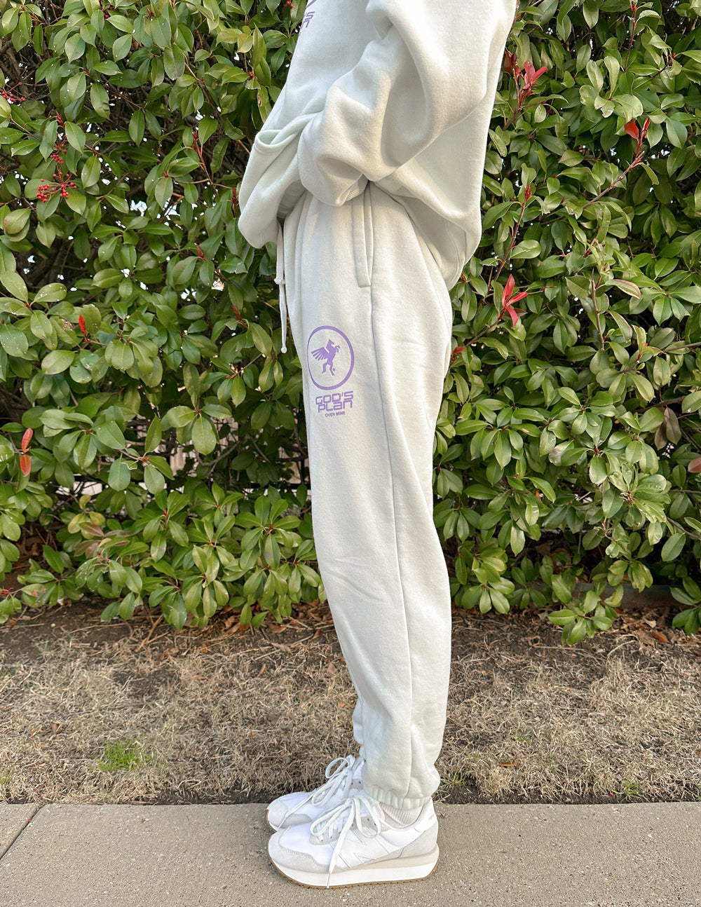 Light cream sweatpants with side purple logo print and tapered ankle cuffs