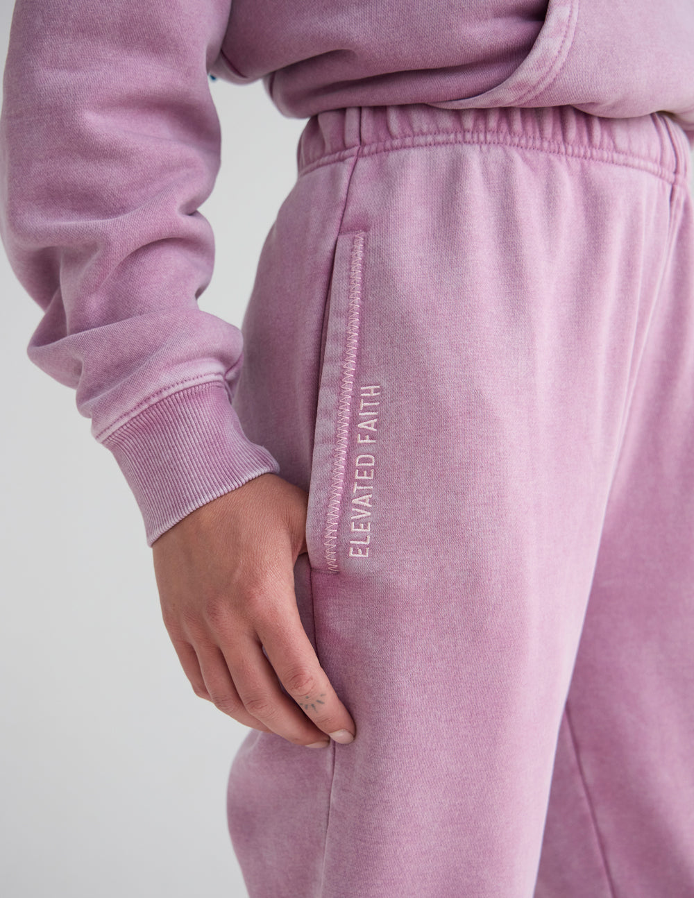 Lavender unisex sweatpants with elastic waistband and vertical logo text on leg