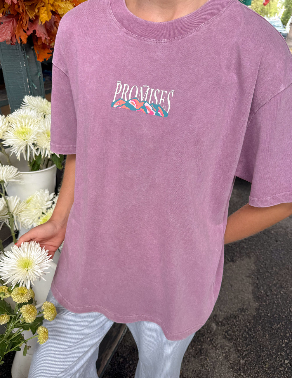 Lavender unisex T-shirt close-up, “Promises” logo with landscape graphic on chest.