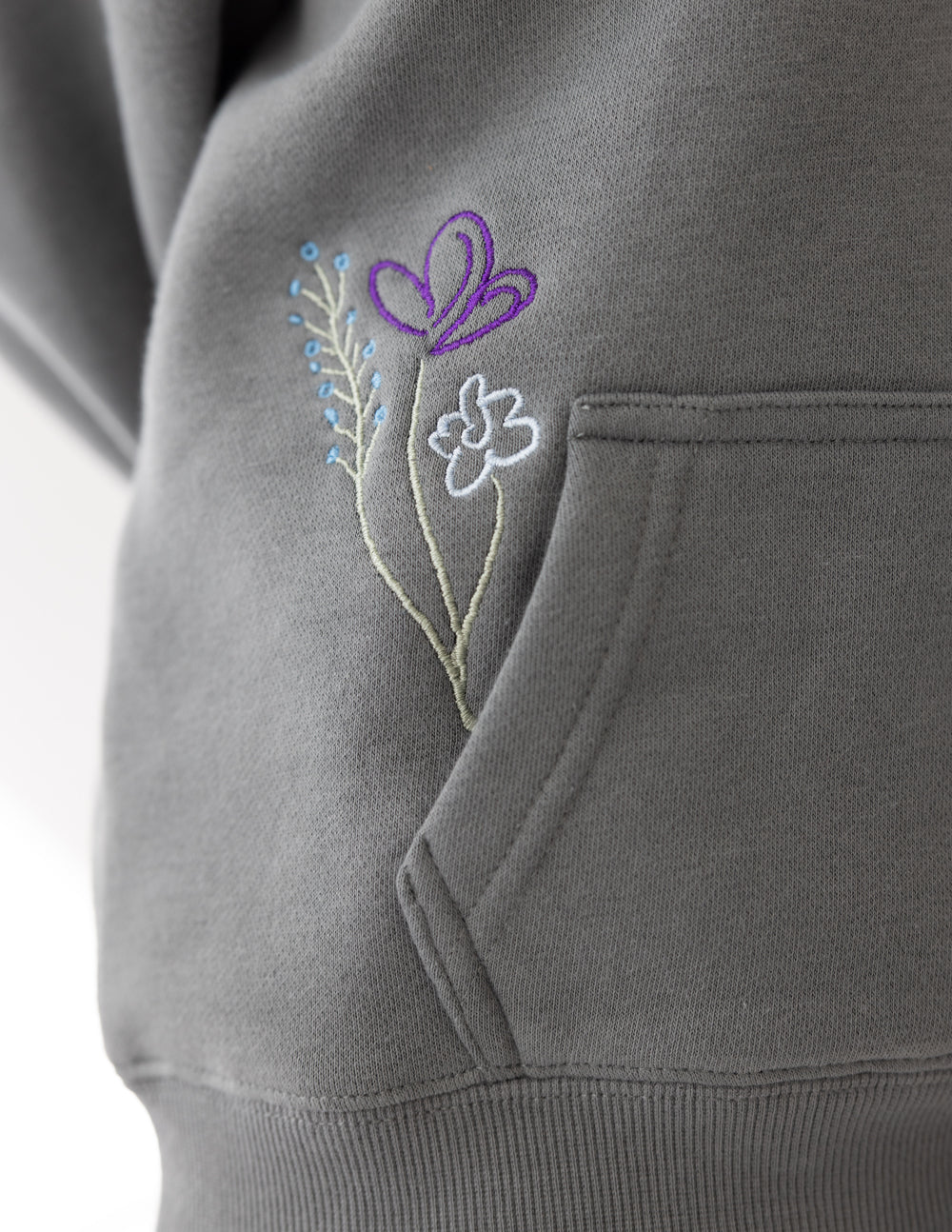 Gray hoodie sleeve with purple, pink, and green flower vine embroidery