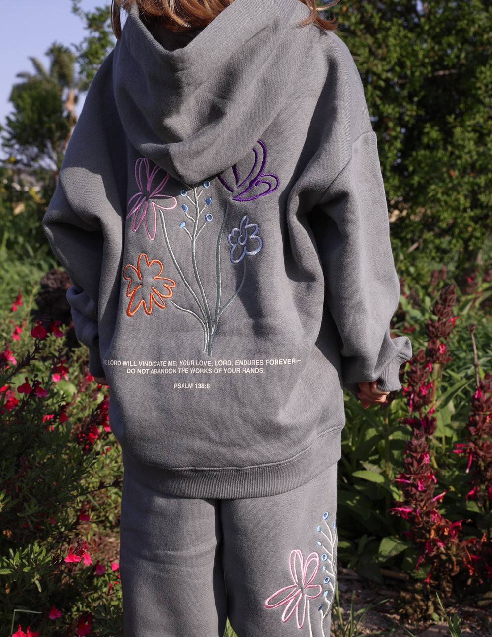 Kids gray hoodie with front pocket and colorful butterfly-flower graphic, hood up.