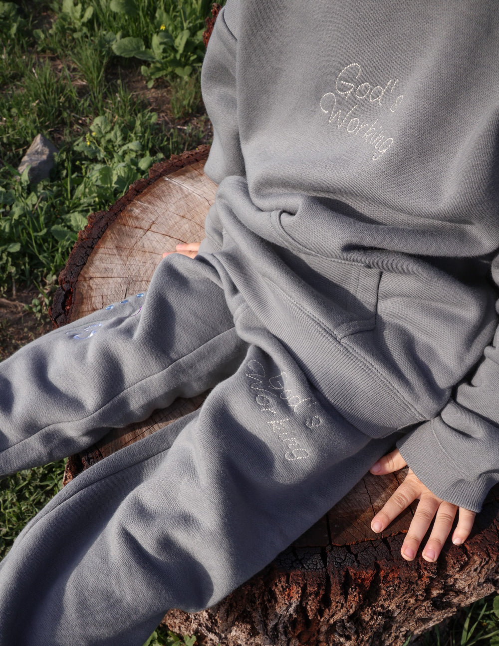 Kids gray sweatpants with embroidered “God’s Still Working” text on thigh