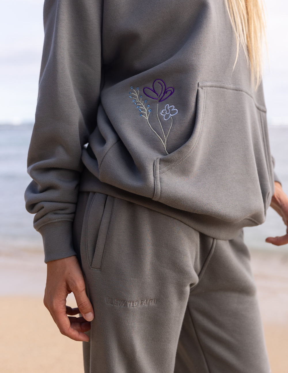 Gray unisex hoodie with colorful floral and heart graphic on the front pocket area.