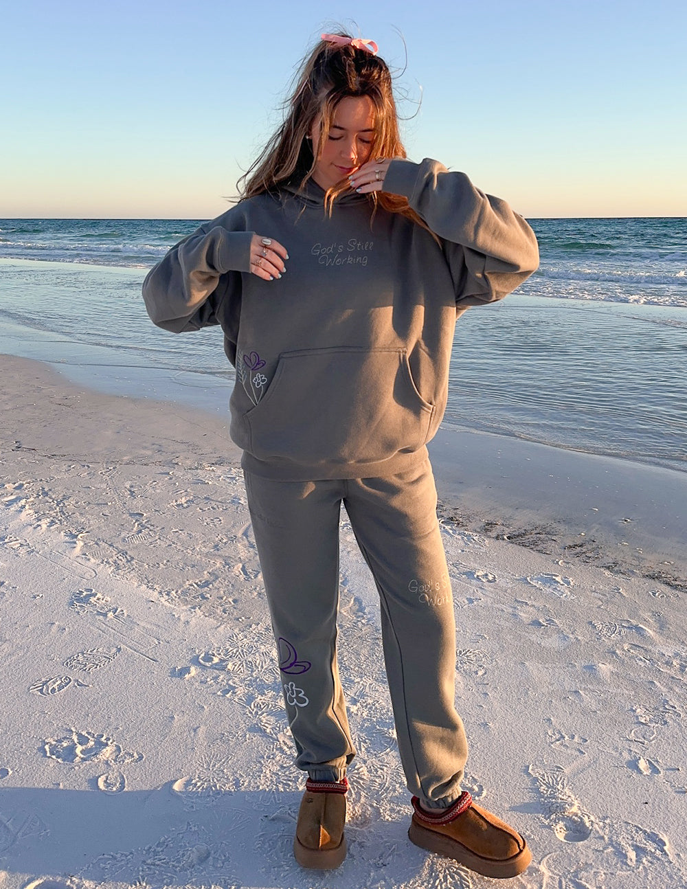 Gray unisex hoodie with hood and front floral text graphic.