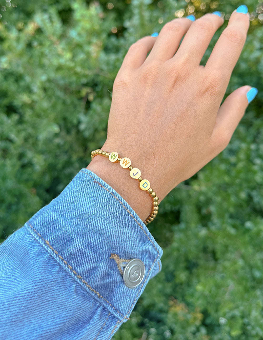 Gold beaded letter bracelet with pastel letter disks on the wrist