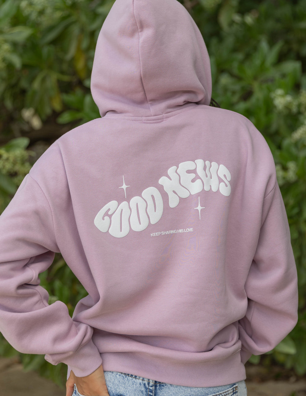 Dusty pink unisex hoodie back with Good News logo, stars, and drawstrings