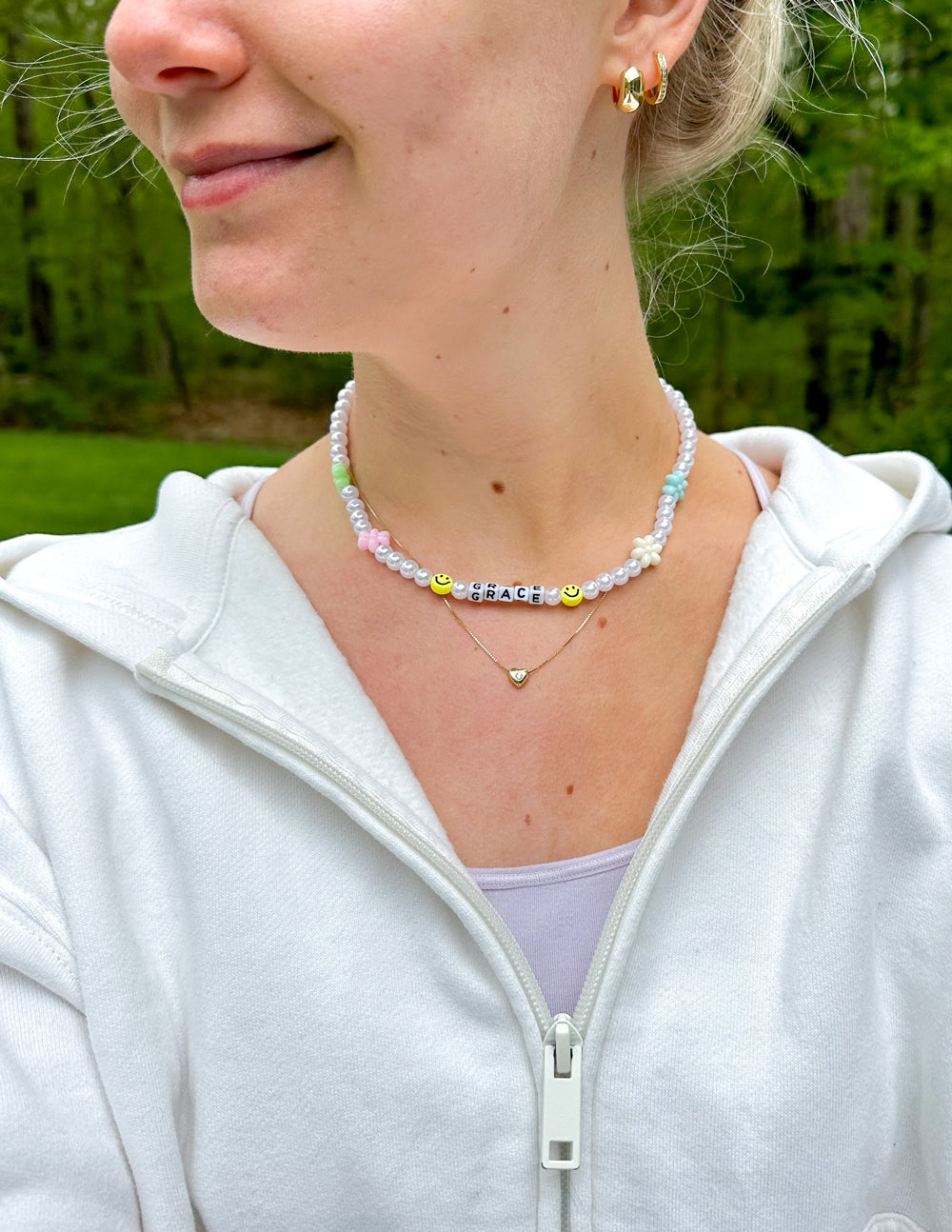 Grace letter necklace worn at collar: white pearl beads with “GRACE” bar and pastel charms