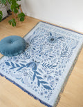 Blue floral throw blanket with fringed border, centered botanical pattern