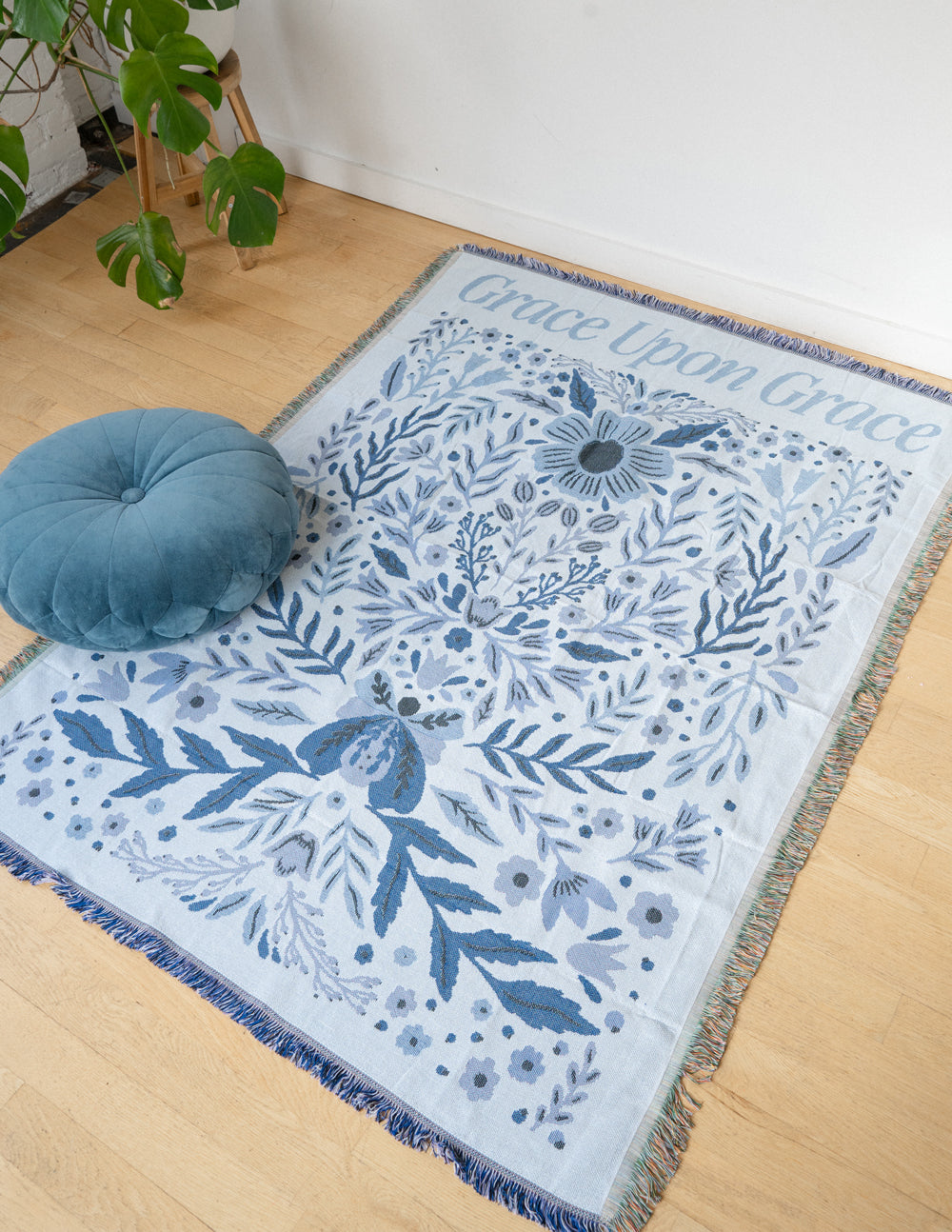 Blue floral throw blanket with fringed border, centered botanical pattern