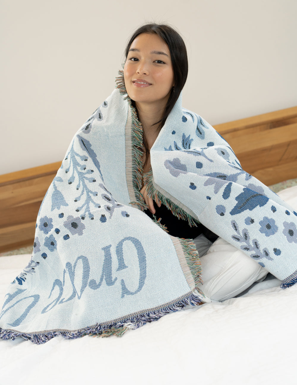 Blue floral throw blanket with fringe trim, folded and wrapped around shoulders