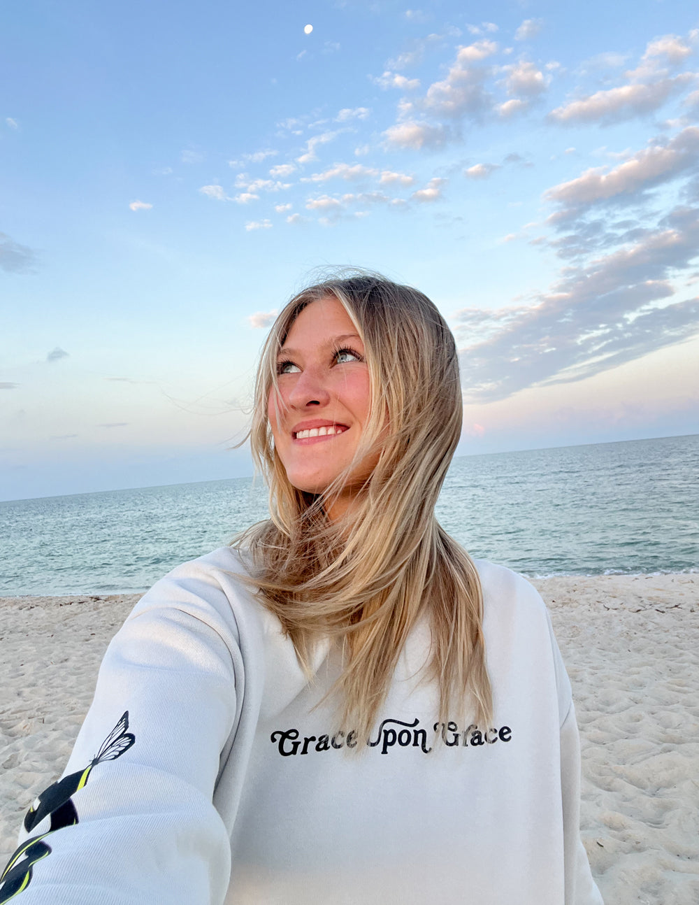 Cream unisex hoodie with chest script and small butterfly graphic, hooded neckline