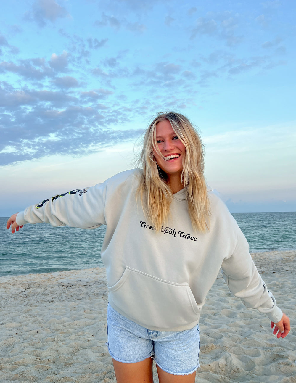 Cream unisex hoodie with hood and front pocket, chest script and butterfly graphic