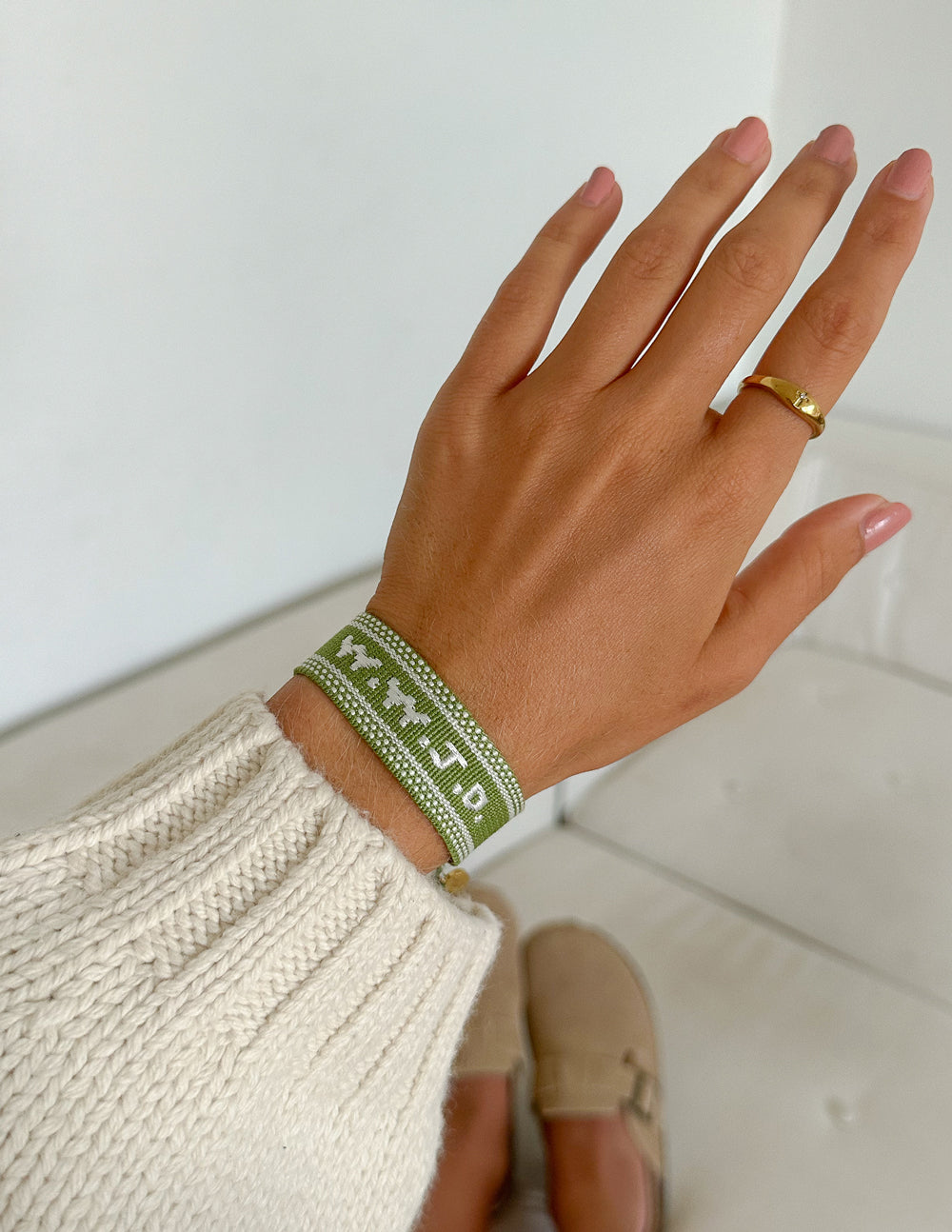Green embroidered bracelet with charm on wrist