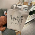 Natural canvas tote bag with long handles and floral text 'Grow in Grace'