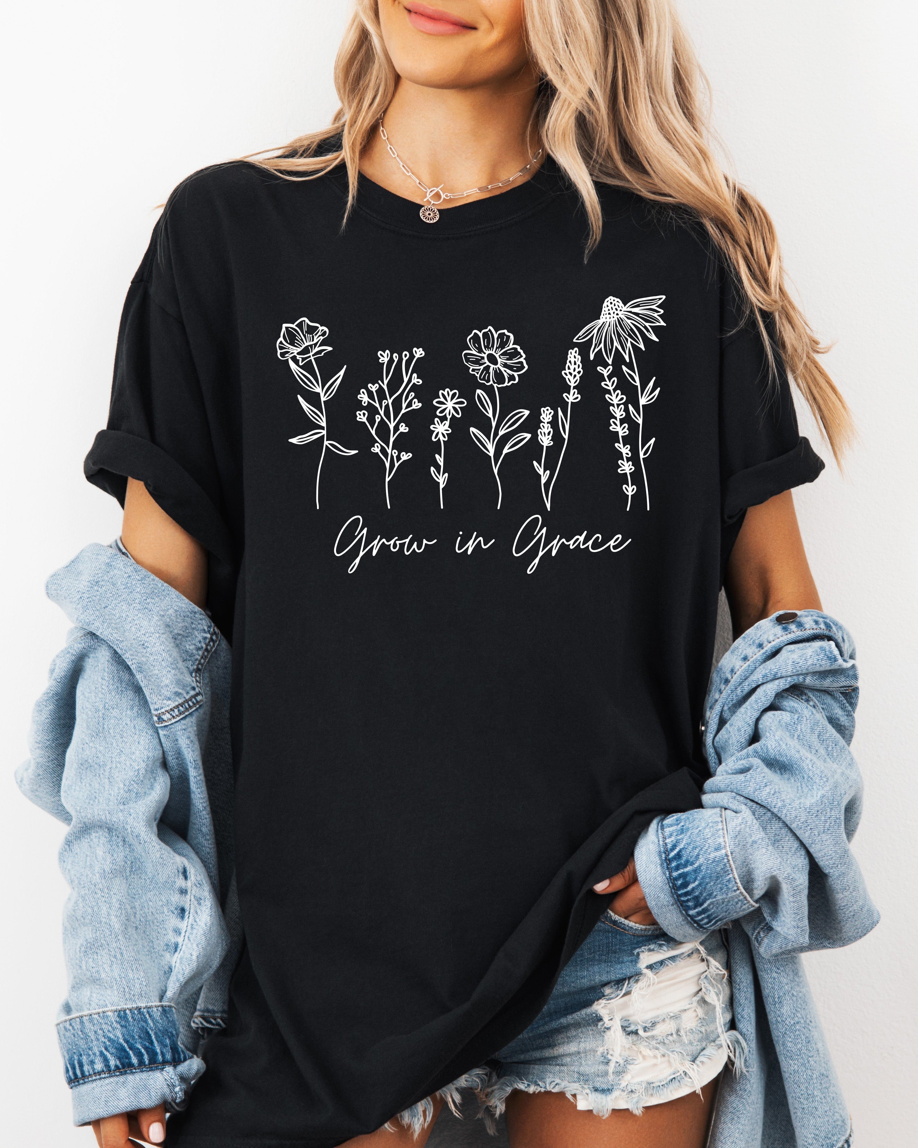Black unisex graphic t-shirt with floral “Grow in Grace” print across chest