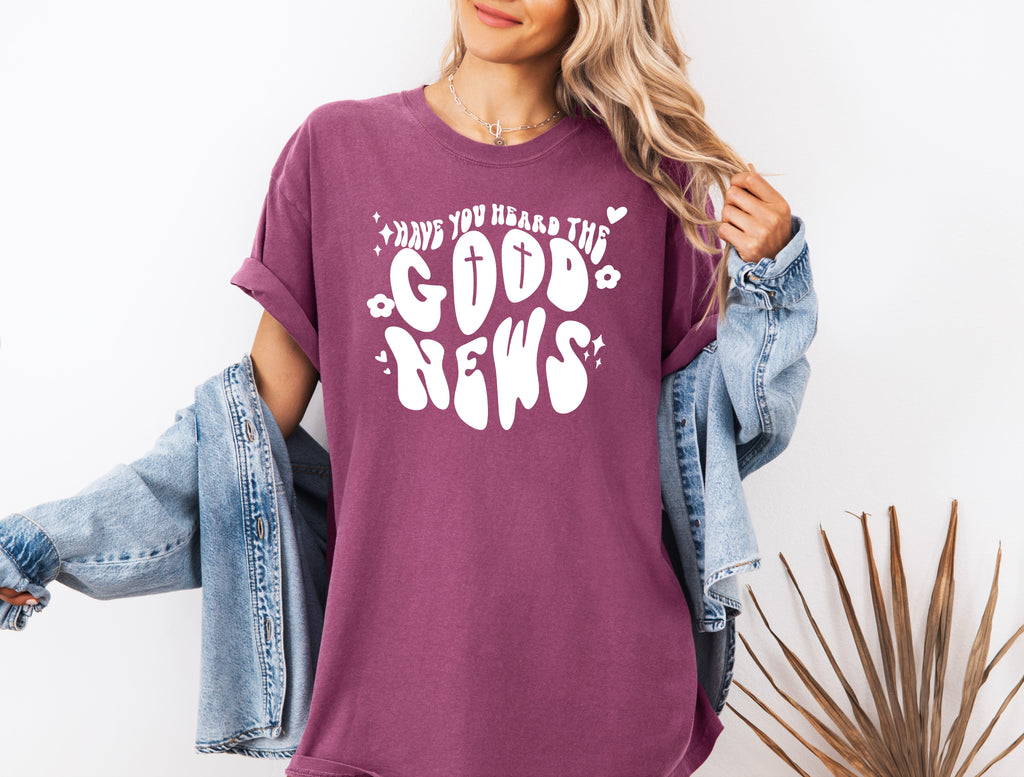 Orchid garment-dyed Christian T-shirt with white front cross and “Good News” graphic