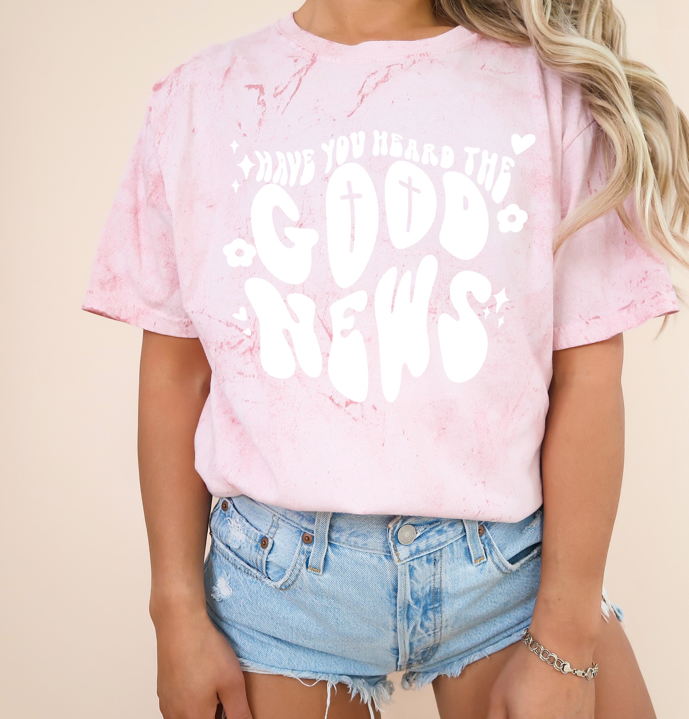 Blush pink garment-dyed Christian T-shirt with white cross and “Good News” front graphic