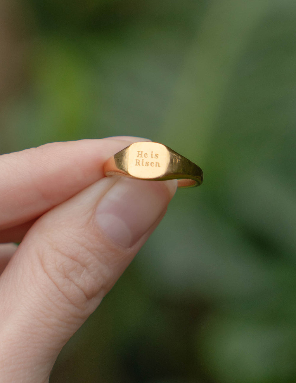 Gold signet ring worn on finger, 'He is Risen' engraved face