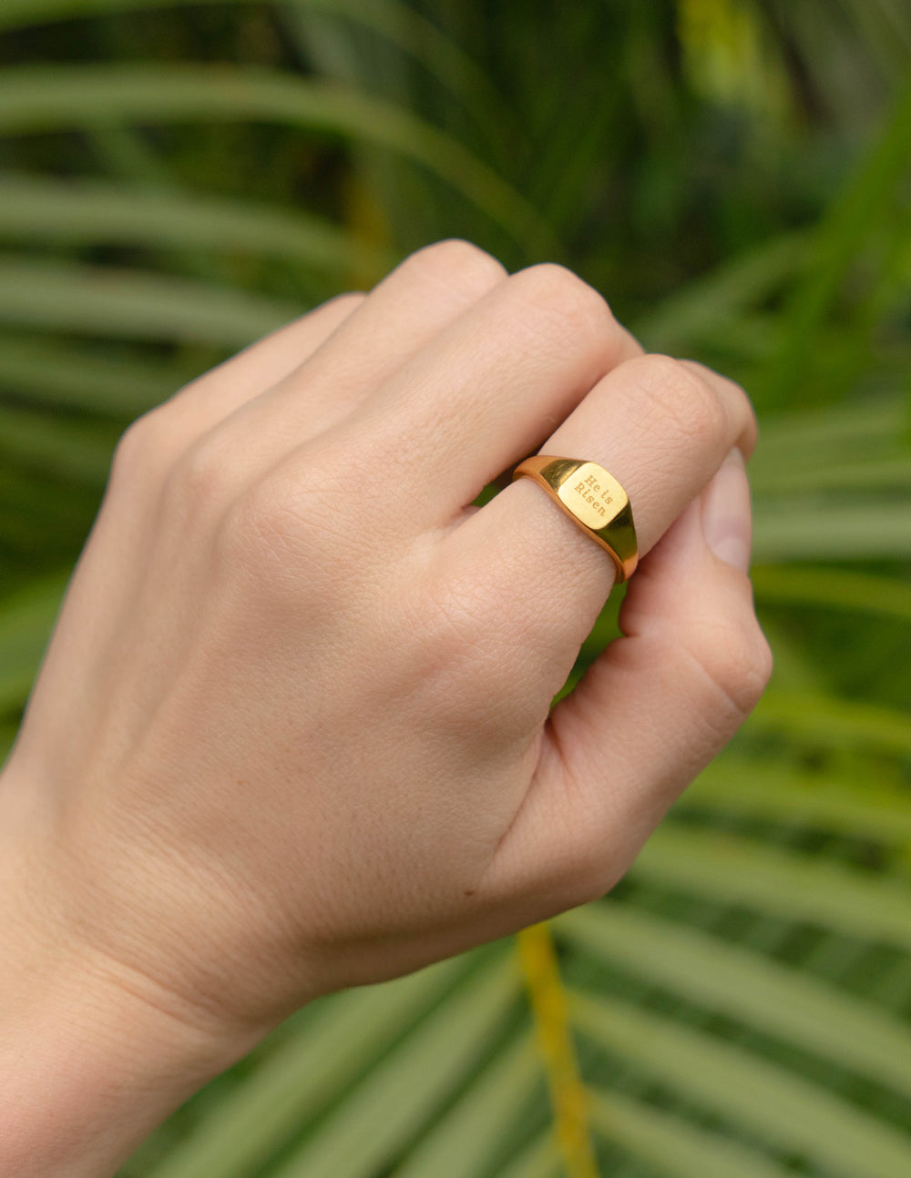 Gold signet ring on finger, 'He is Risen' engraving on front