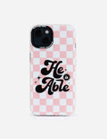 Pink checkered phone case with 'He is Able' lettering and camera cutouts