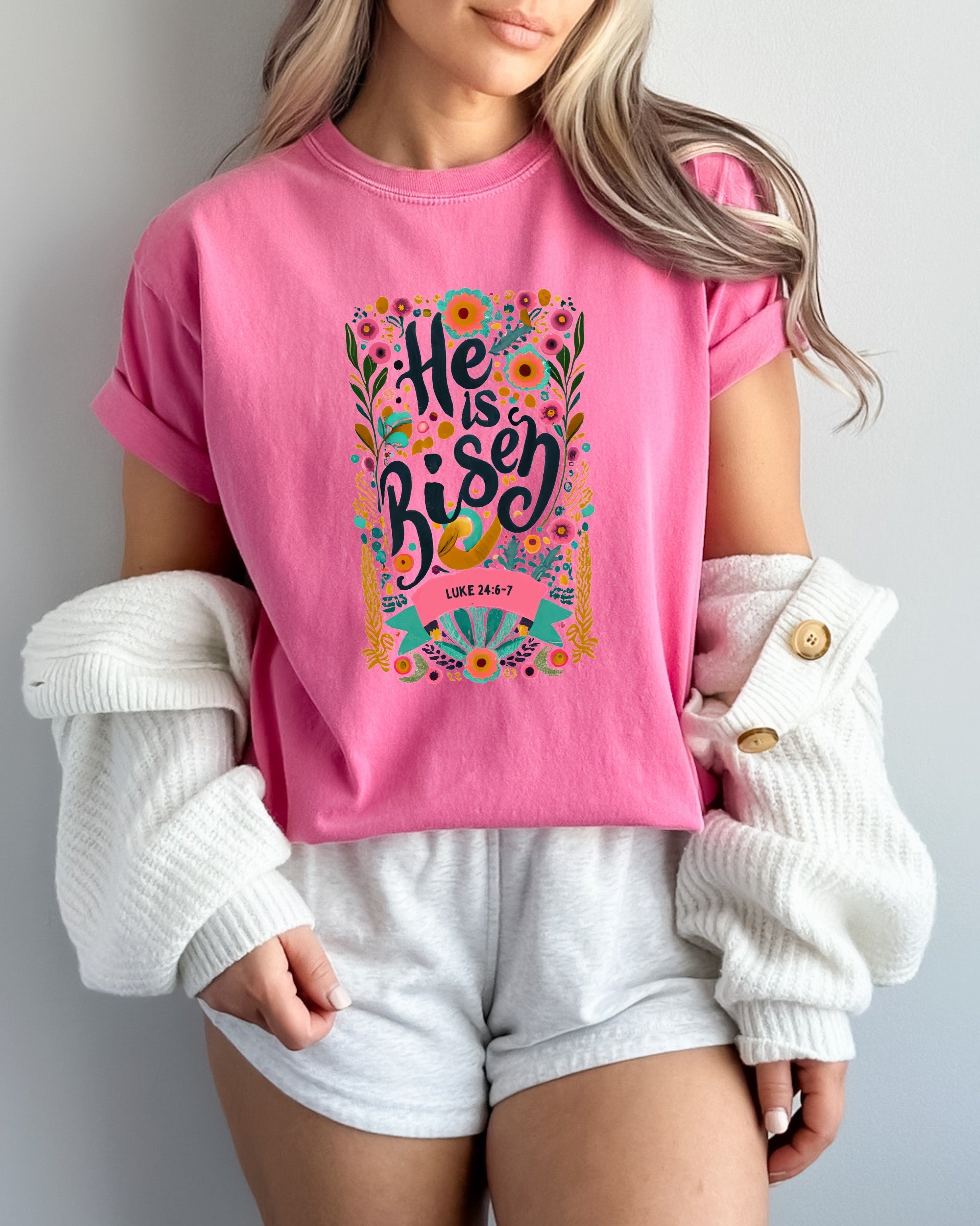 Pink crewneck Christian T-shirt with colorful "He is Risen" floral graphic and Luke 24:6-7