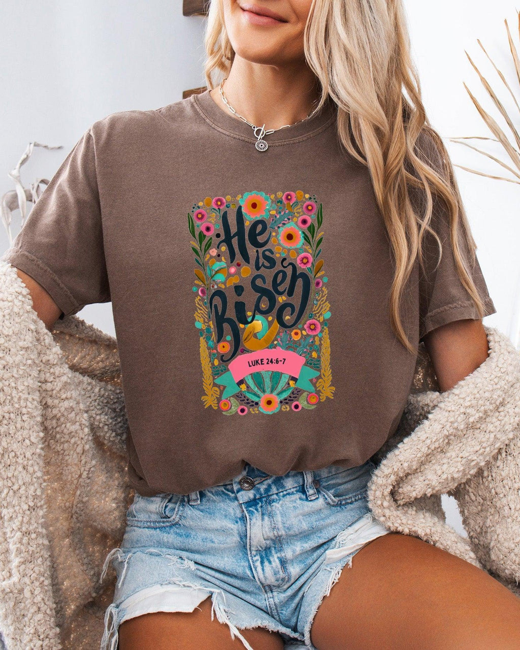 Garment-dyed dark brown unisex T-shirt with colorful "He is Risen" front graphic