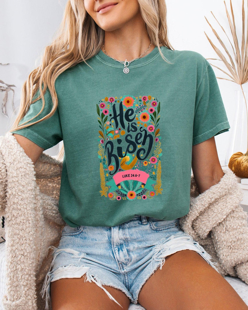 Garment-dyed green unisex T-shirt with colorful "He is Risen" front graphic