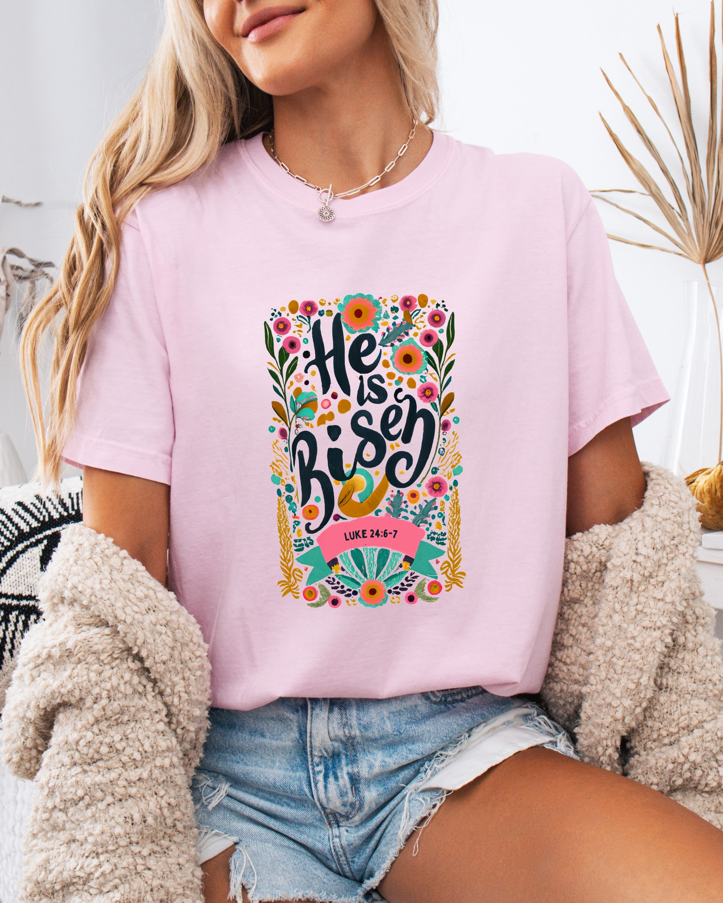 Lavender crewneck Christian T-shirt with colorful "He is Risen" floral graphic and Luke 24:6-7