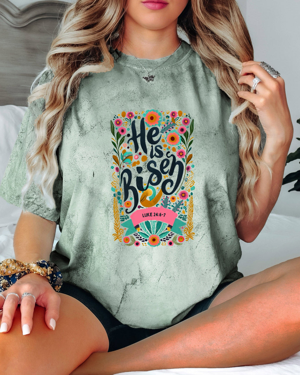 Green crewneck Christian T-shirt with colorful "He is Risen" floral graphic and Luke 24:6-7