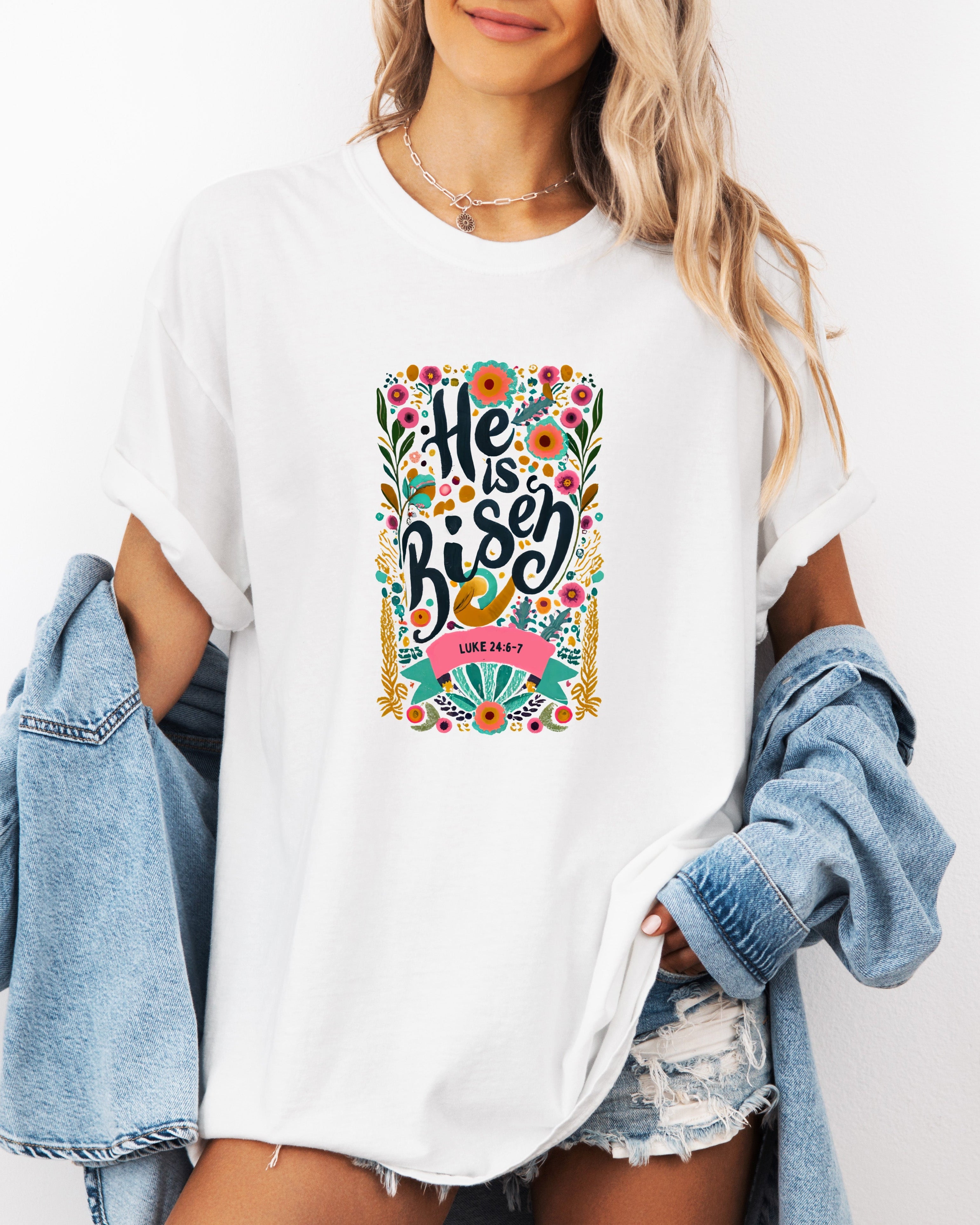 White crewneck Christian T-shirt with colorful "He is Risen" floral graphic and Luke 24:6-7