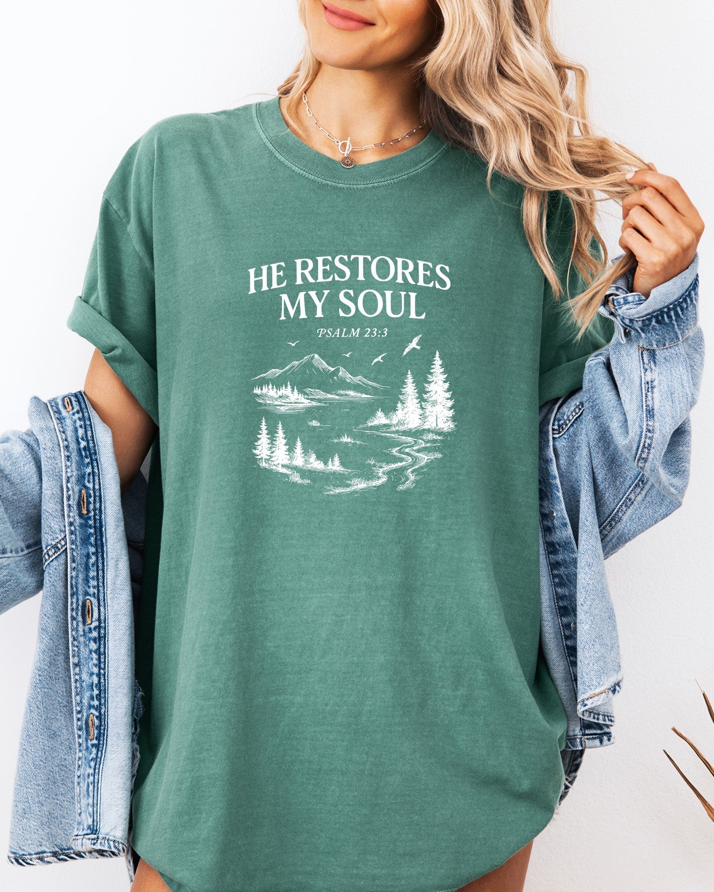 Green unisex T-shirt with white “He Restores My Soul” mountain and pine graphic