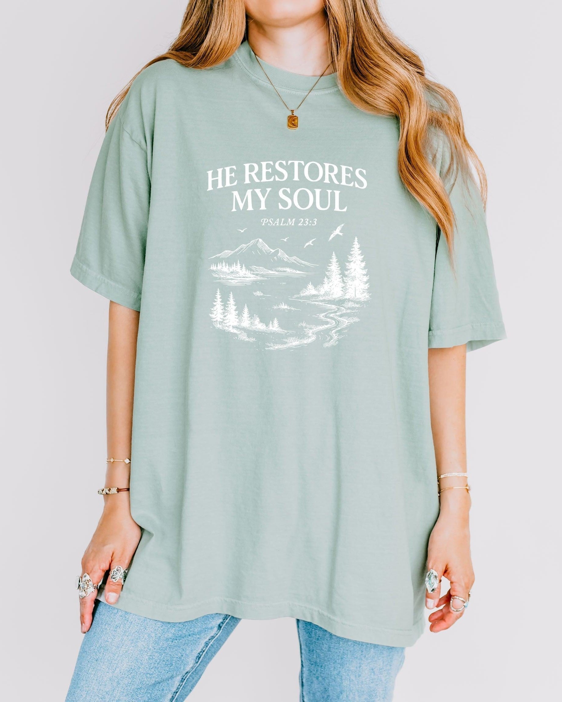 Light green unisex T-shirt with white “He Restores My Soul” mountain landscape graphic