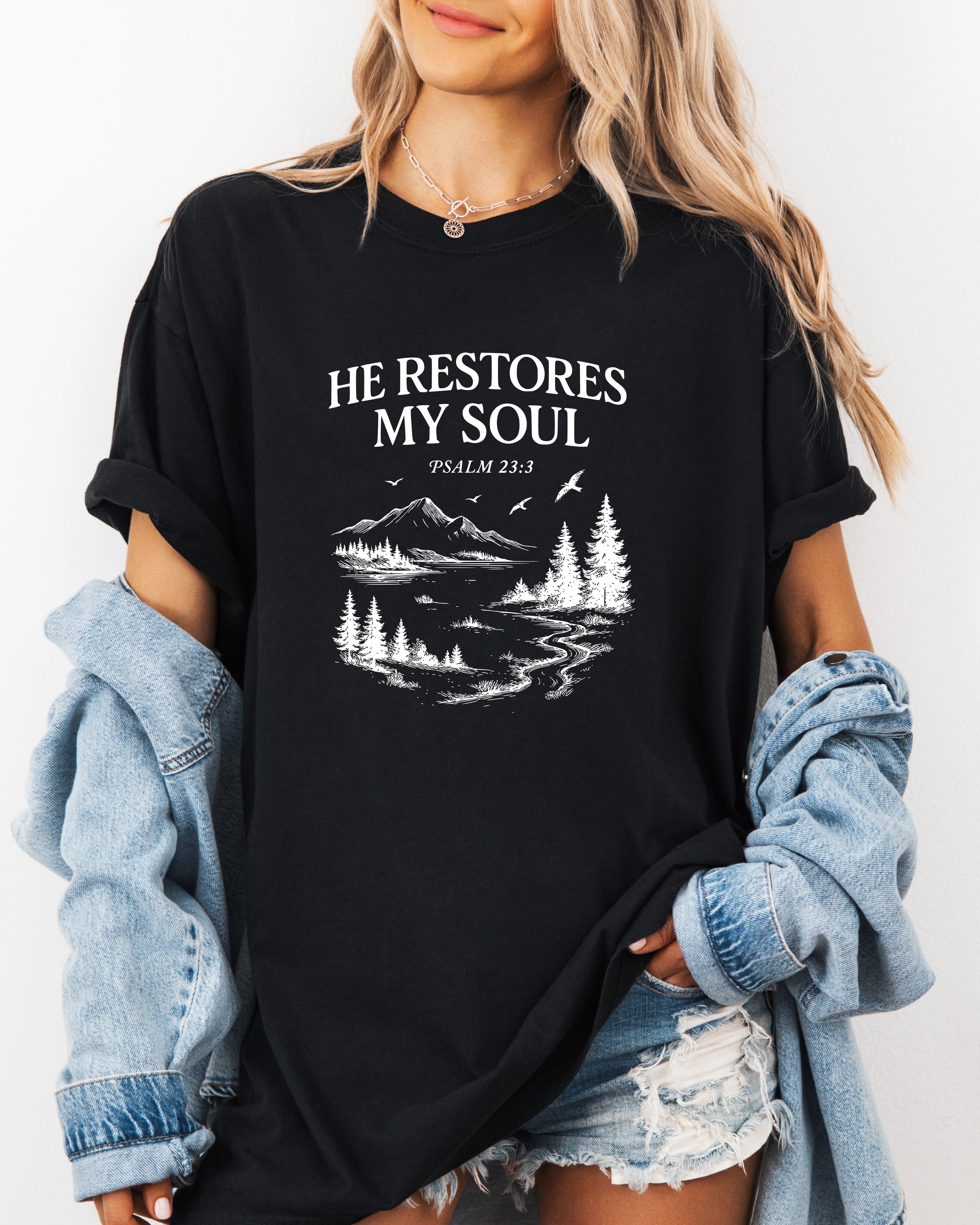 Black unisex T-shirt with white “He Restores My Soul” landscape graphic, crew neck