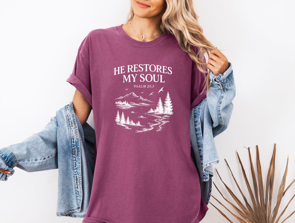 Purple unisex T-shirt with white “He Restores My Soul” mountain and tree graphic, crew neck