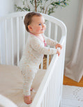 Off-white heart-print footed onesie with pink front zipper and long sleeves.