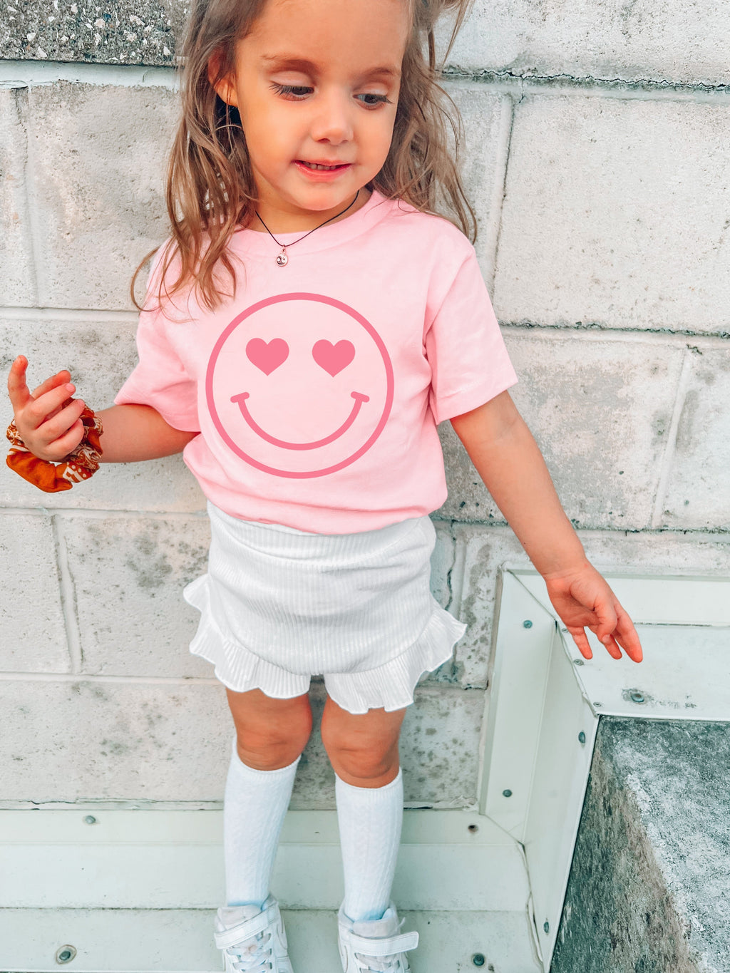 Pink baby girl t-shirt with white heart-eyed smiley face graphic