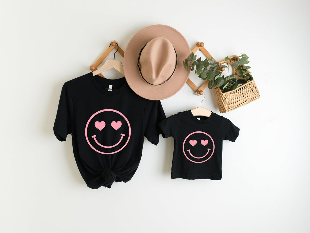 Set of black baby girl t-shirts with pink heart-eyed smiley face graphics