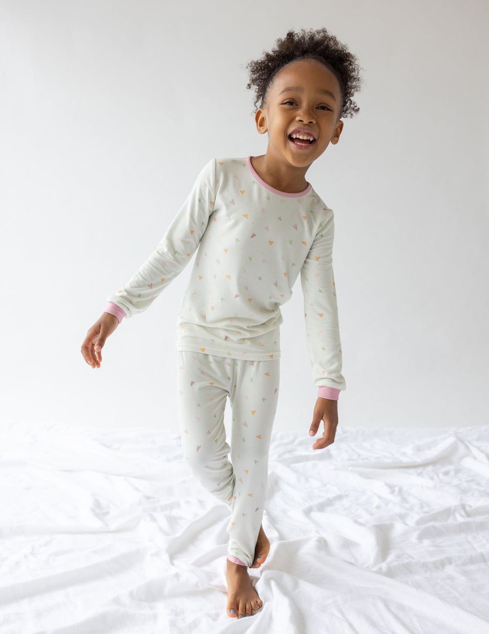 Kids long-sleeve pajama set in light cream with scattered heart print and pink cuffs