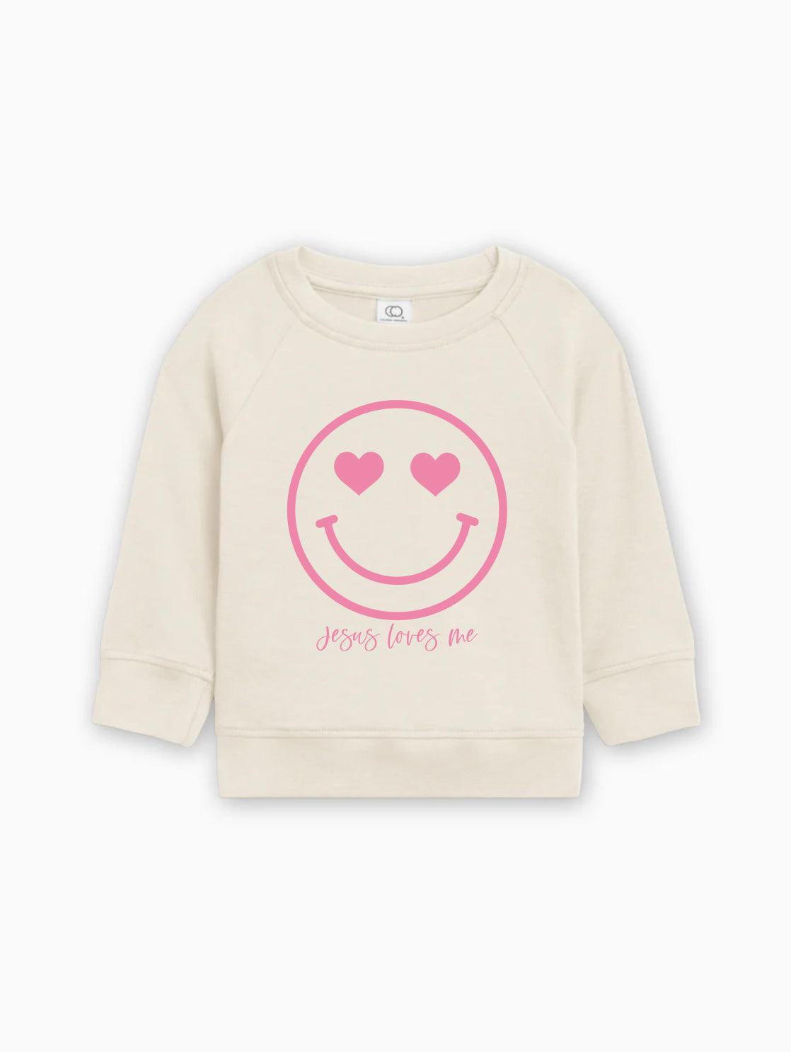 Cream kids organic cotton pullover with pink heart smiley graphic and 'Jesus loves me'