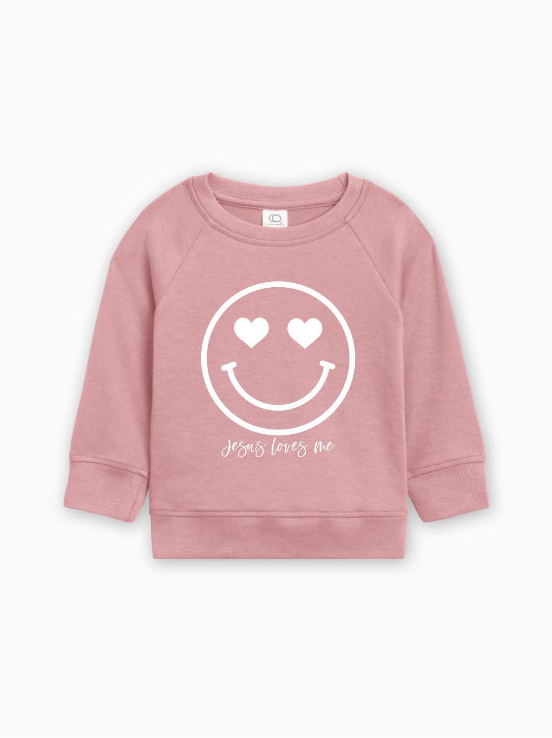 Pink kids organic cotton pullover with heart smiley graphic and 'Jesus loves me' text