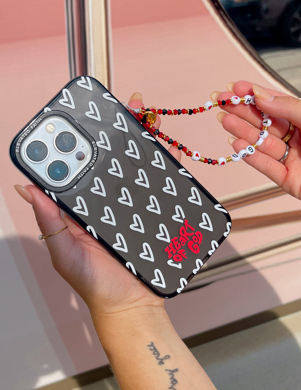 Beaded phone charm with red and white beads on black phone case with white hearts