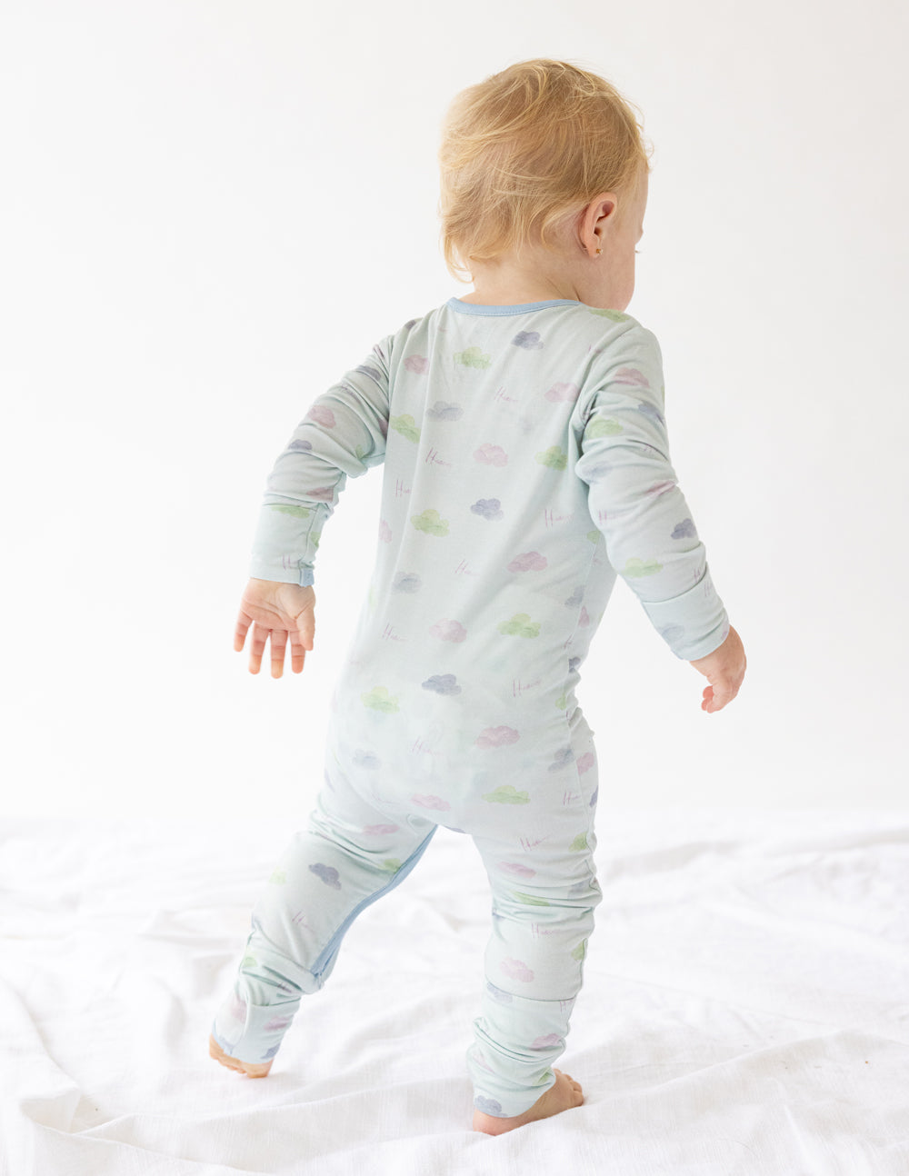 Light blue baby footed onesie with pastel icon print, back view
