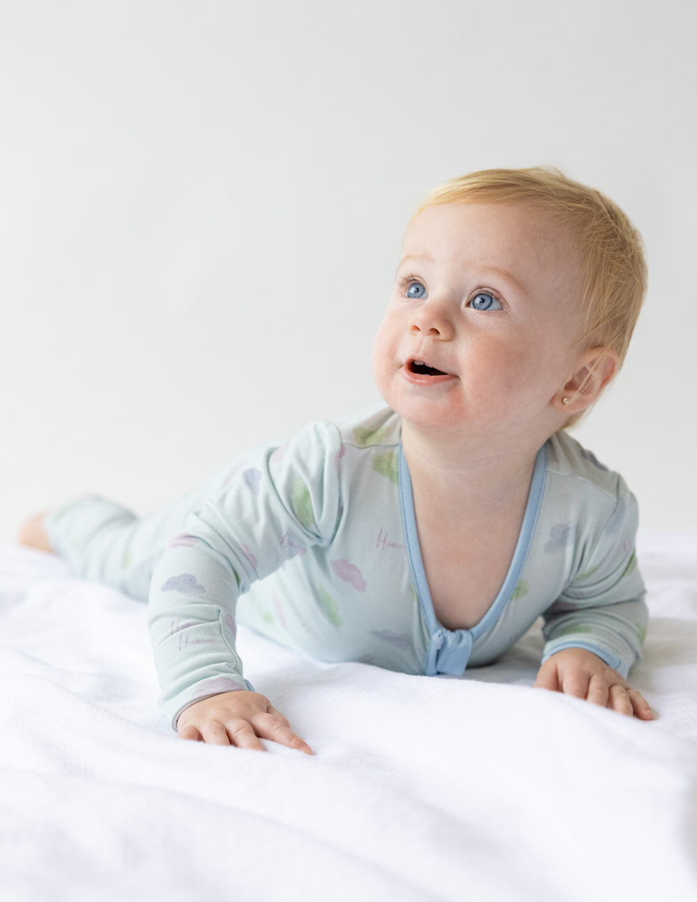 Light blue baby footed onesie with pastel icon print and V-neck zipper placket